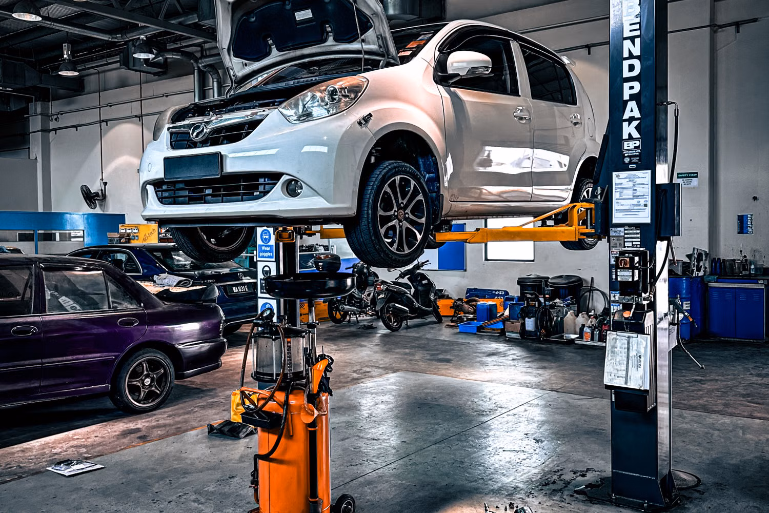 A vehicle raised on a hydraulic lift in a professional auto repair shop